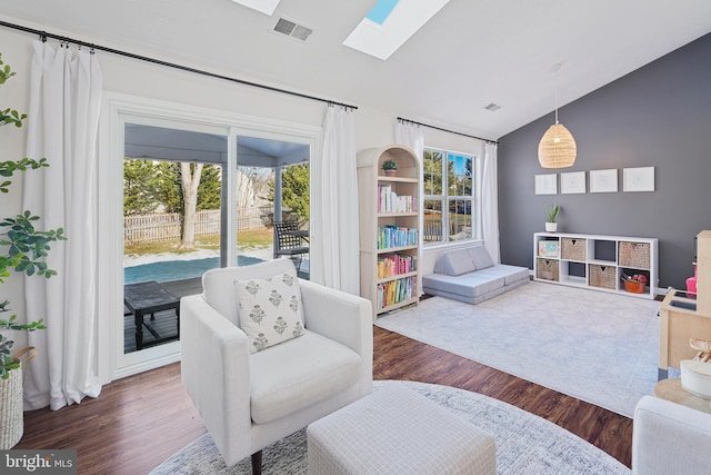 living area featuring dark hardwood / wood-style flooring and vaulted ceiling with skylight