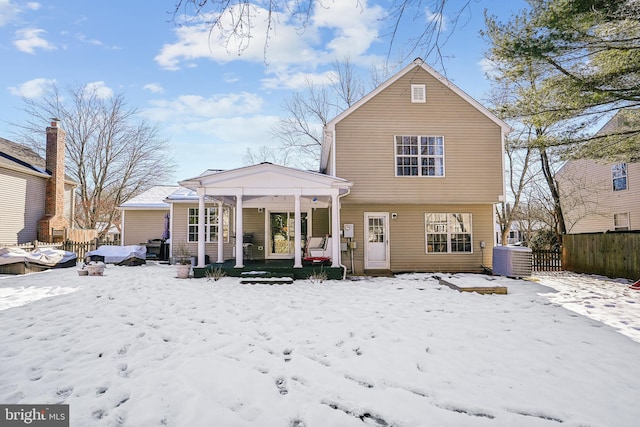 snow covered back of property with covered porch and central air condition unit