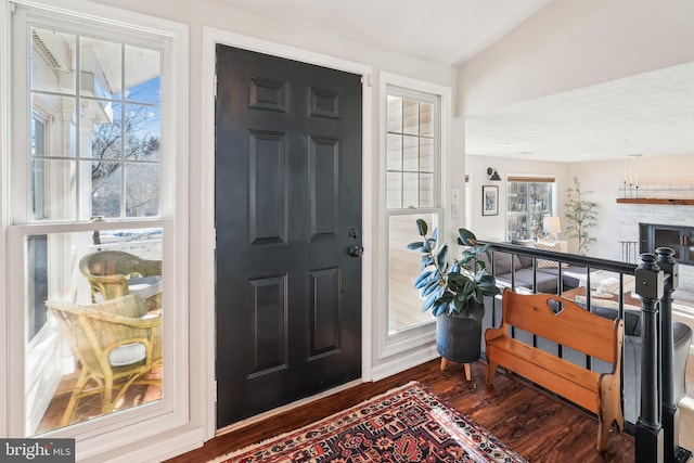 entrance foyer featuring hardwood / wood-style flooring, vaulted ceiling, and a brick fireplace