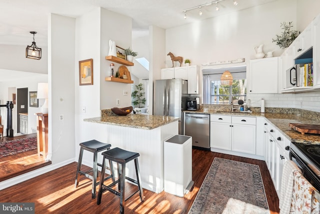 kitchen with kitchen peninsula, stainless steel appliances, dark wood-type flooring, and white cabinetry