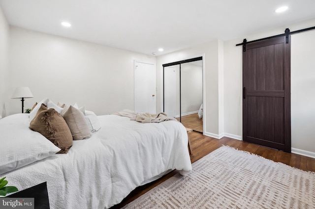 bedroom with hardwood / wood-style flooring, a barn door, and a closet