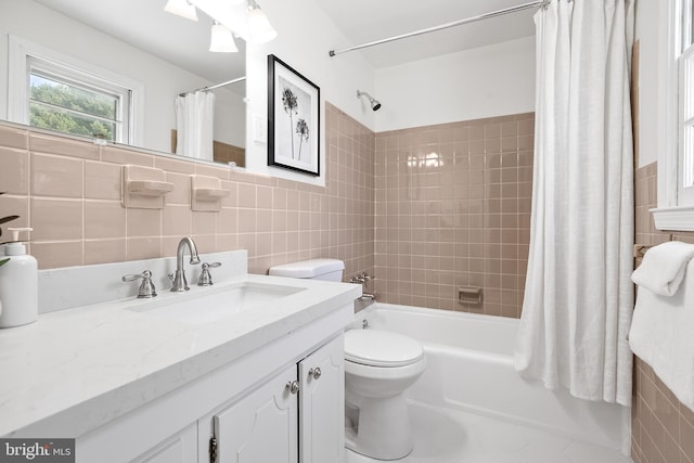 full bathroom with vanity, toilet, tile walls, and shower / tub combo