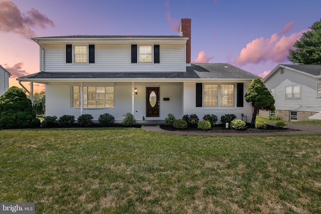 view of front of home with a porch and a lawn