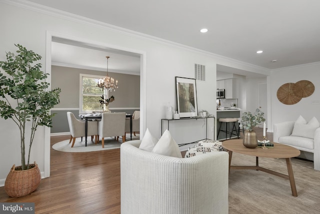 living room featuring a chandelier, hardwood / wood-style flooring, and crown molding