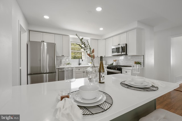 kitchen featuring sink, dark hardwood / wood-style floors, tasteful backsplash, white cabinetry, and stainless steel appliances