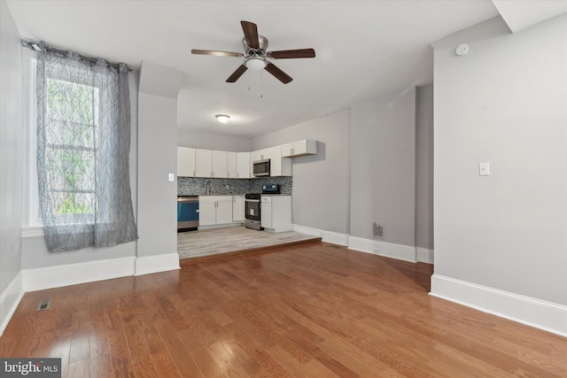 unfurnished living room featuring plenty of natural light, ceiling fan, and light wood-type flooring