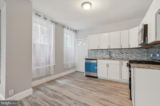 kitchen featuring dark stone counters, backsplash, white cabinetry, and stainless steel appliances