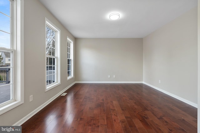 spare room featuring dark hardwood / wood-style flooring and plenty of natural light