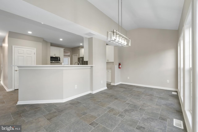 interior space with vaulted ceiling, decorative light fixtures, white cabinetry, stainless steel appliances, and a chandelier