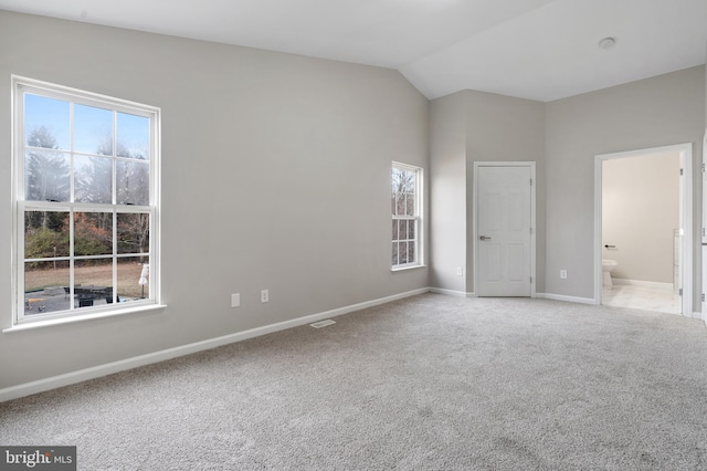 unfurnished bedroom featuring ensuite bathroom, carpet, and lofted ceiling