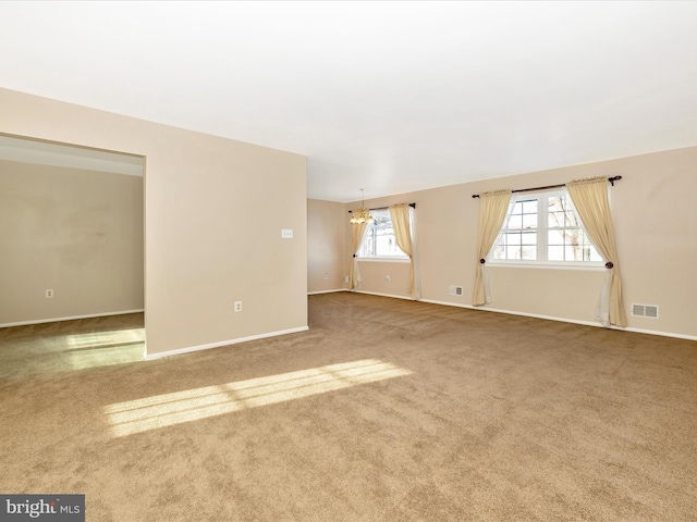 empty room featuring carpet and a notable chandelier