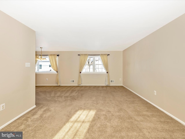 spare room featuring light carpet and a notable chandelier