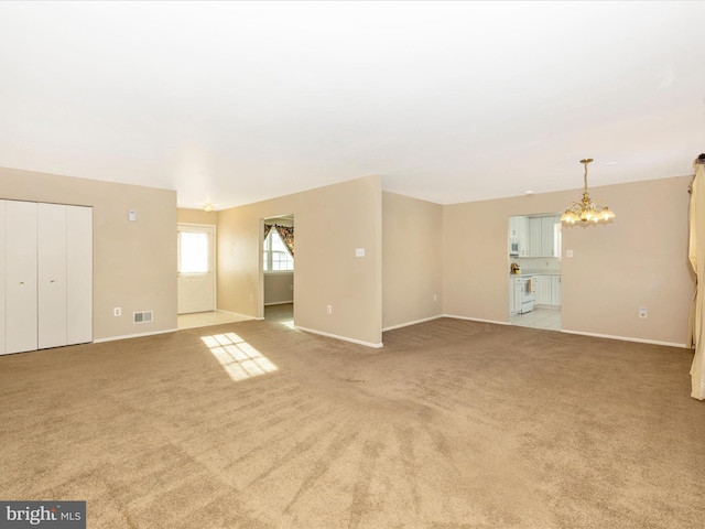 empty room featuring light colored carpet and a chandelier