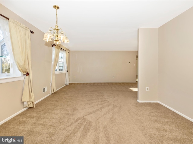 spare room featuring light colored carpet and an inviting chandelier