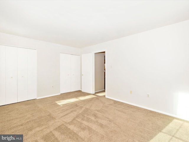 unfurnished bedroom with light carpet and two closets