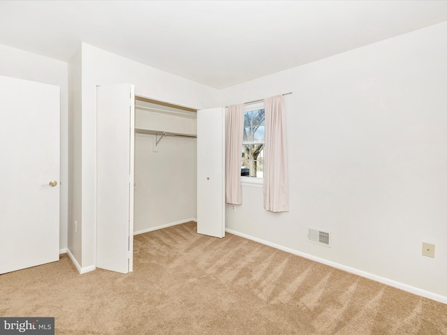 unfurnished bedroom with light colored carpet and a closet