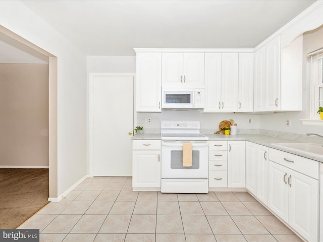 kitchen with light tile patterned floors, white appliances, white cabinetry, and sink