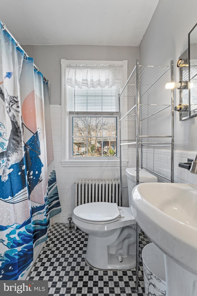 bathroom with sink, a shower with shower curtain, toilet, tile walls, and radiator heating unit