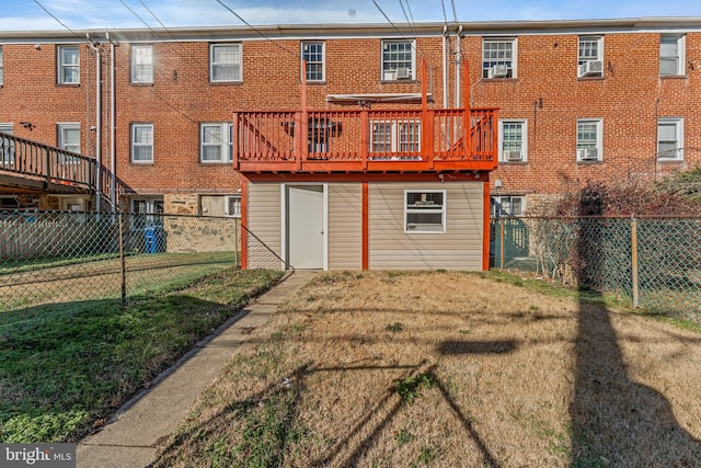 rear view of property featuring a wooden deck and a lawn