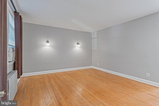 unfurnished room featuring wood-type flooring, radiator, and cooling unit