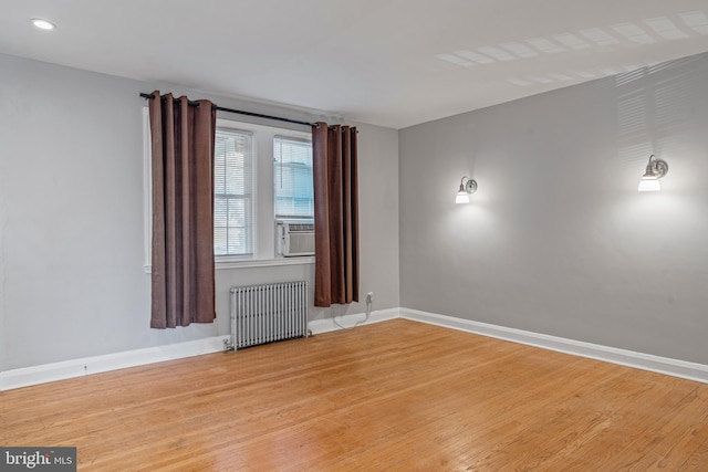 spare room featuring radiator heating unit, cooling unit, and hardwood / wood-style floors