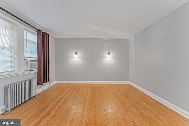 empty room featuring cooling unit, light wood-type flooring, and radiator