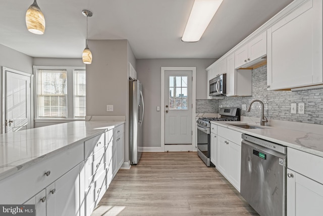 kitchen featuring light stone countertops, white cabinetry, pendant lighting, and appliances with stainless steel finishes