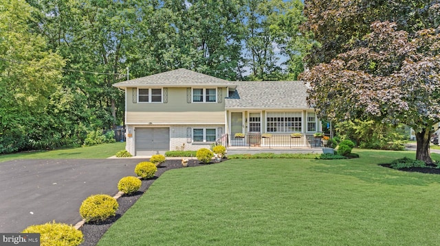 tri-level home with a garage, covered porch, and a front lawn