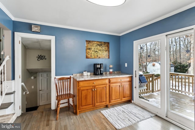 bar featuring ornamental molding and light hardwood / wood-style flooring