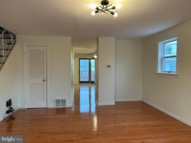 spare room featuring ceiling fan with notable chandelier and wood-type flooring