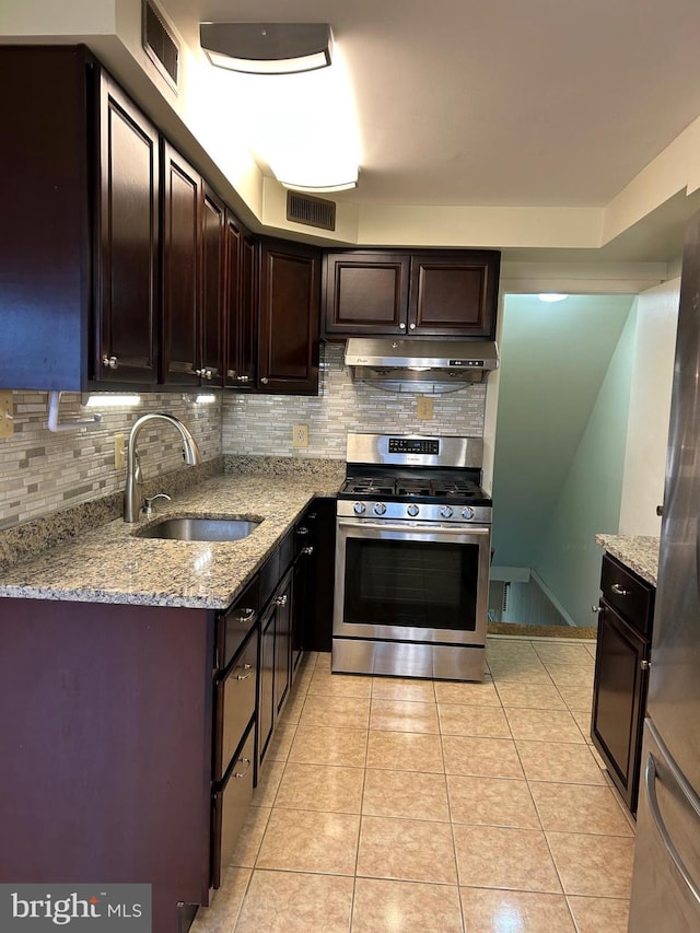 kitchen with light stone countertops, tasteful backsplash, sink, light tile patterned floors, and stainless steel range with gas stovetop