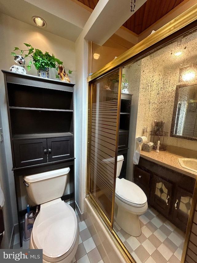 bathroom featuring toilet, a shower with shower door, and sink