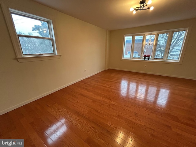 spare room featuring a chandelier and hardwood / wood-style flooring