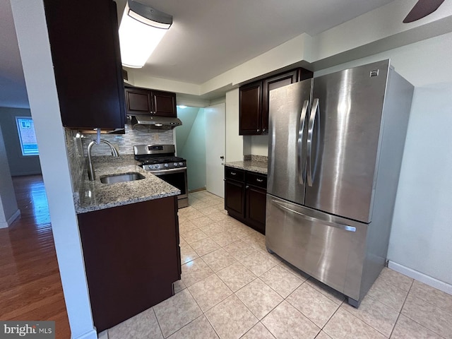 kitchen featuring backsplash, light stone counters, dark brown cabinetry, stainless steel appliances, and sink