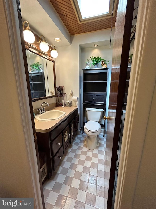 bathroom with vanity, a skylight, toilet, and wood ceiling