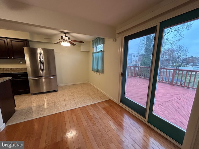 kitchen with ceiling fan, stainless steel fridge, light wood-type flooring, a wealth of natural light, and dark brown cabinets