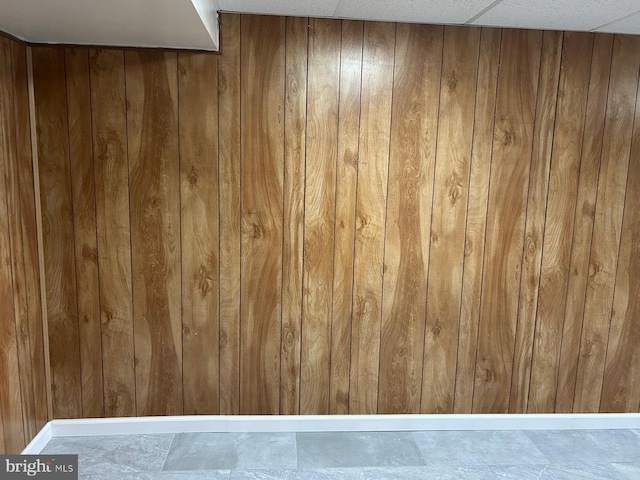 interior details with a paneled ceiling and wooden walls