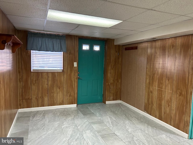 entryway featuring a drop ceiling and wooden walls