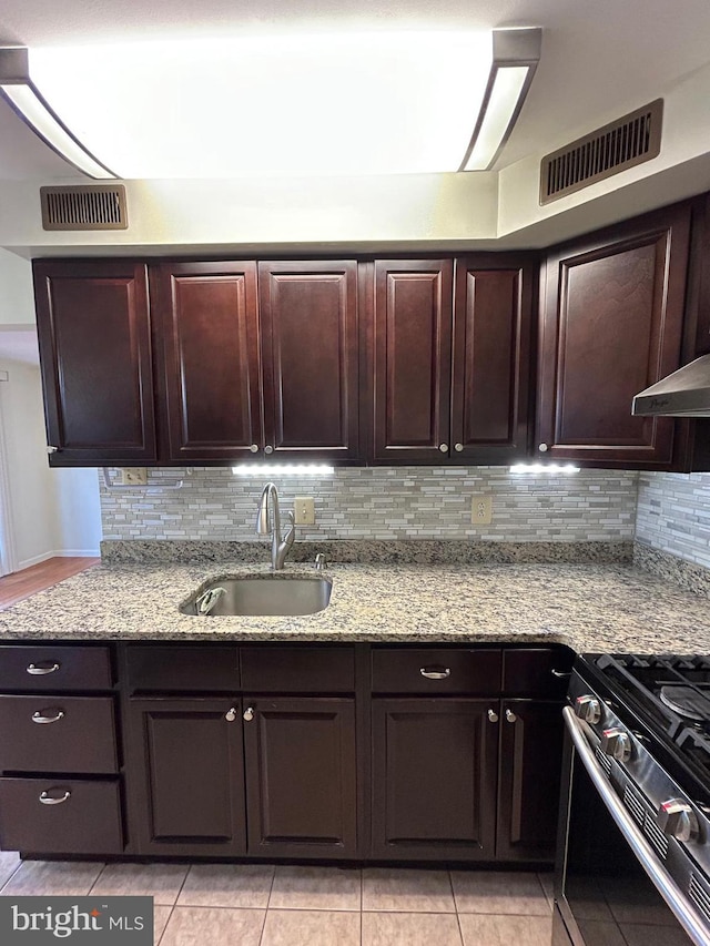 kitchen featuring backsplash, light stone countertops, sink, and light tile patterned floors