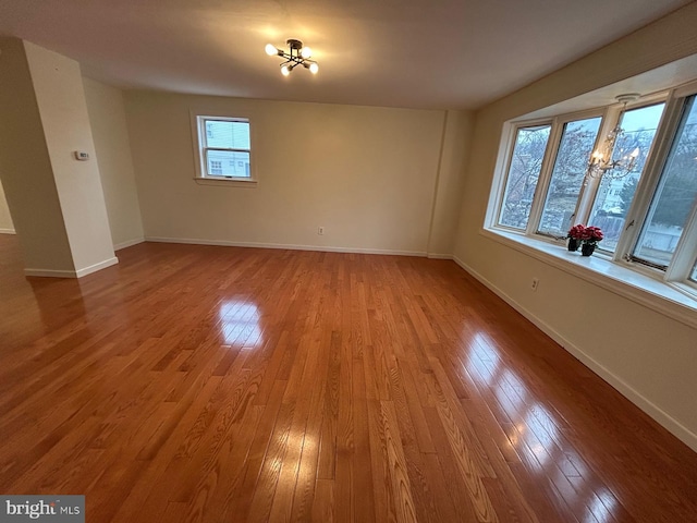 empty room featuring light wood-type flooring and a notable chandelier