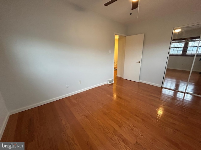 unfurnished bedroom with ceiling fan, a closet, and dark hardwood / wood-style floors