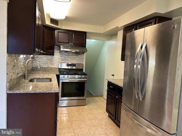 kitchen featuring tasteful backsplash, light stone counters, sink, and appliances with stainless steel finishes