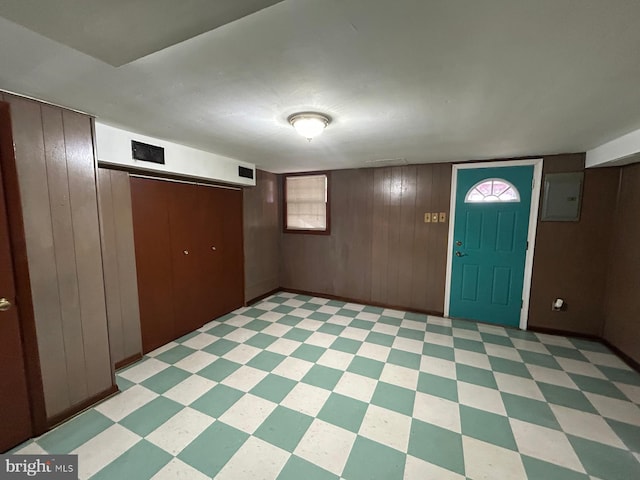 foyer entrance featuring electric panel and wood walls