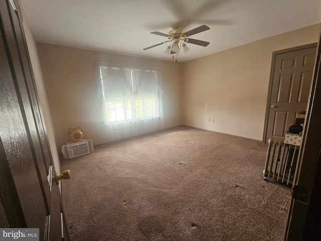 empty room with dark colored carpet, ceiling fan, and a wall unit AC