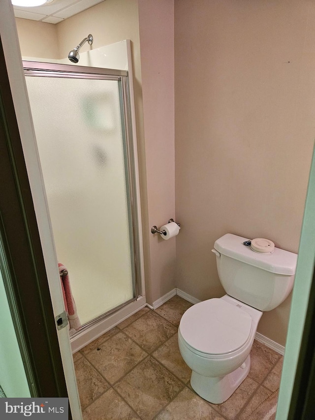 bathroom featuring a shower with door and toilet