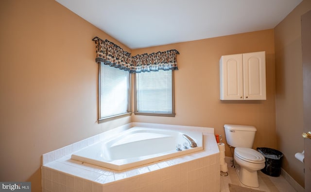 bathroom featuring tiled tub, tile patterned floors, and toilet