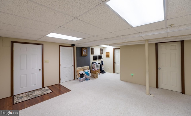 basement with a paneled ceiling and carpet floors