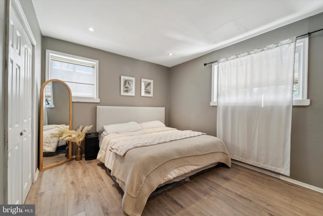 bedroom with multiple windows, a closet, and light hardwood / wood-style flooring