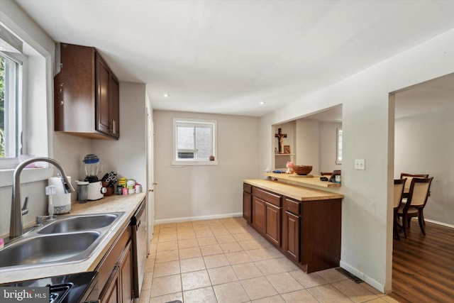 kitchen featuring dishwasher, sink, light tile patterned floors, and range