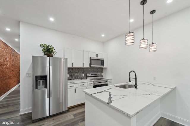 kitchen featuring sink, kitchen peninsula, decorative light fixtures, white cabinets, and appliances with stainless steel finishes